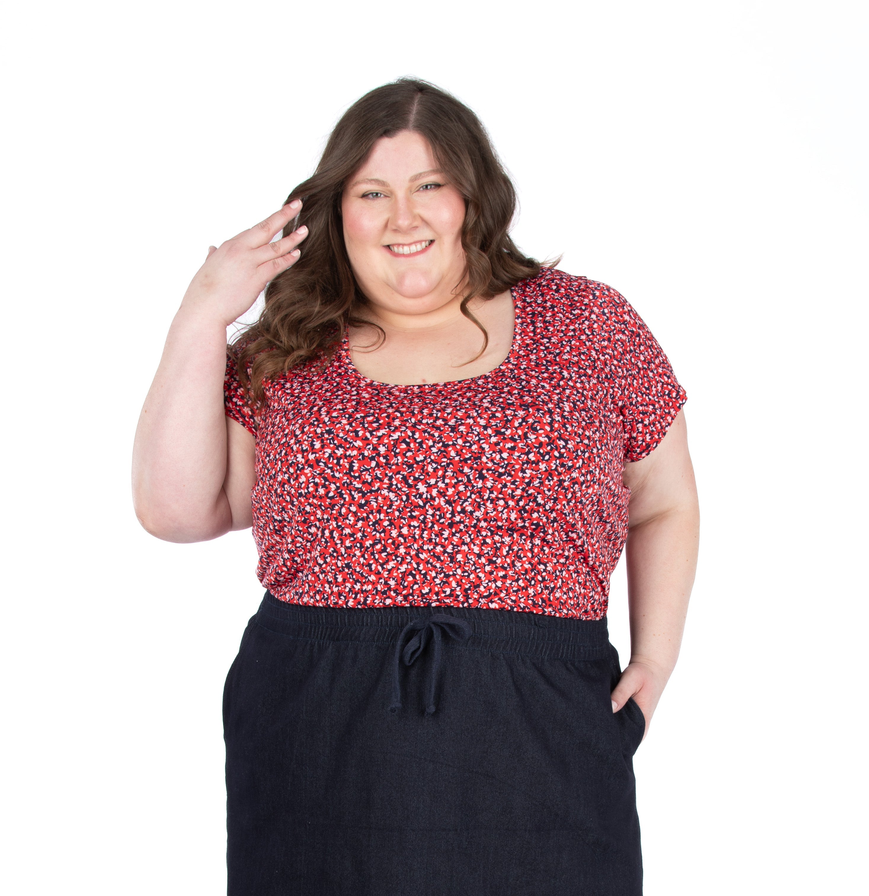 Woman wearing a scoop neck red floral top and black skirt