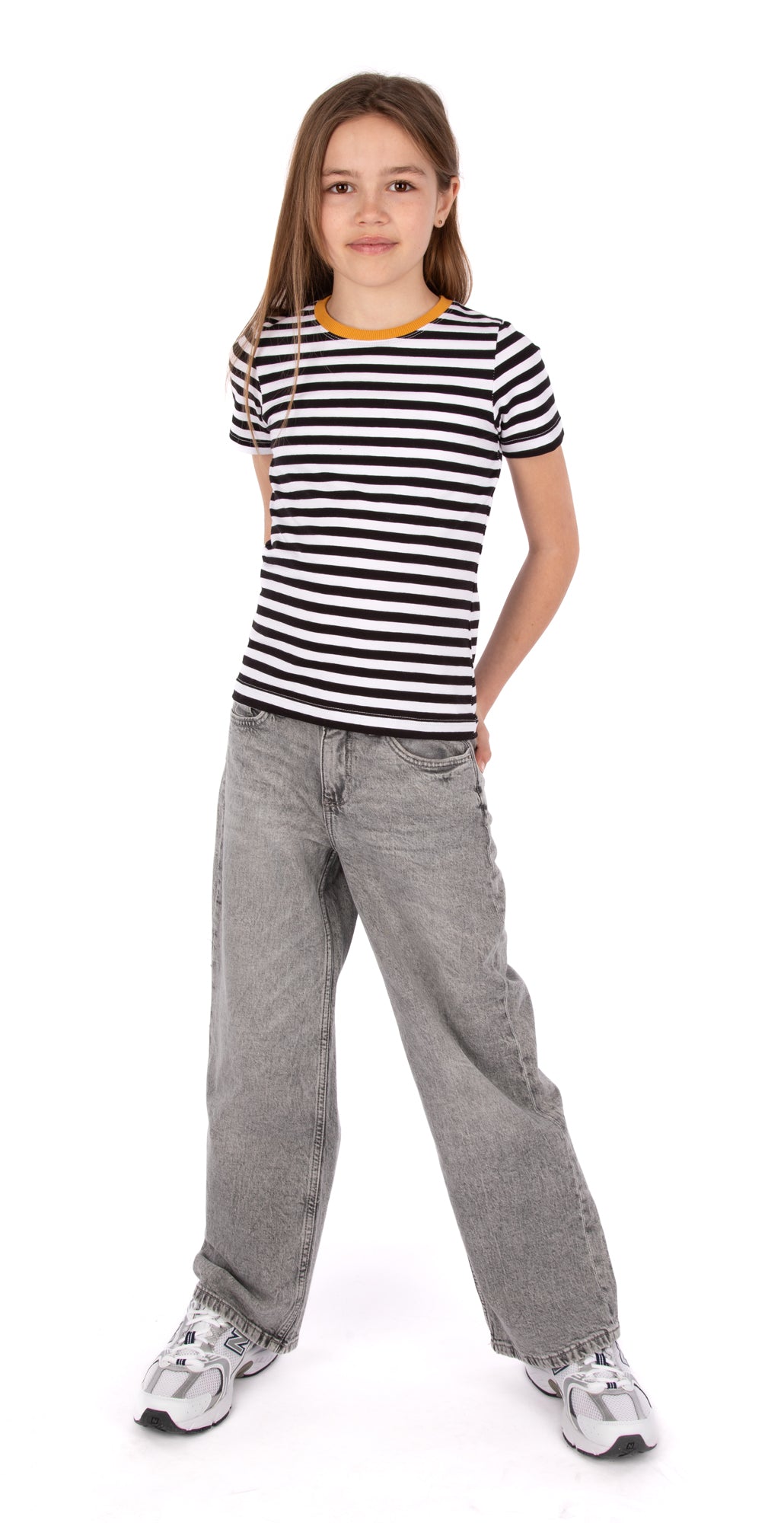 Young girl wearing a black and white striped shirt with a yellow trim on a white background