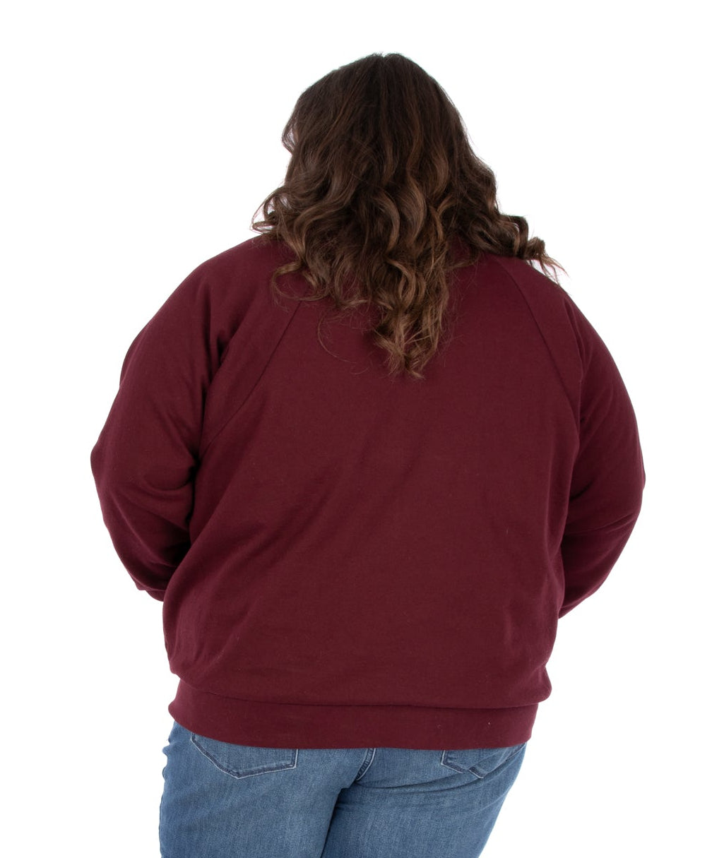 Person wearing a maroon sweatshirt and blue jeans on a white background