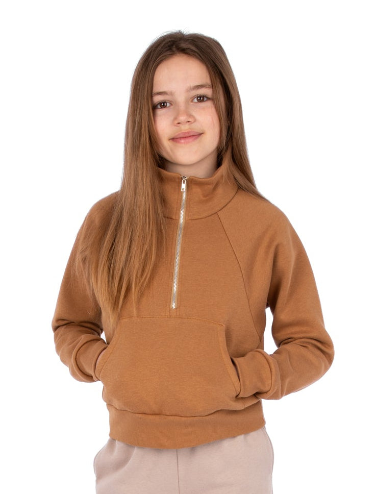 Person wearing a brown hoodie and beige pants on a white background